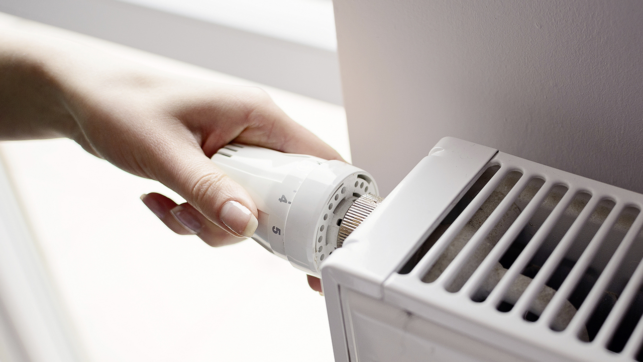 vrouwenhand draait aan verwarmingsknop